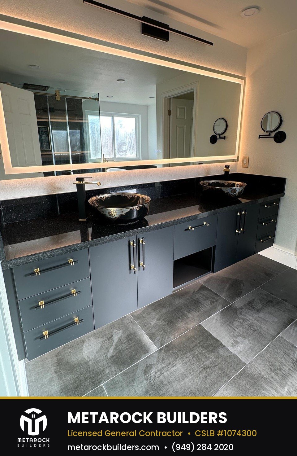 Bathroom remodel in Orange County by Sunward Builders Inc., completed after photo with navy shaker vanity, black quartz counters, vessel sinks, brushed brass hardware, and backlit LED mirror