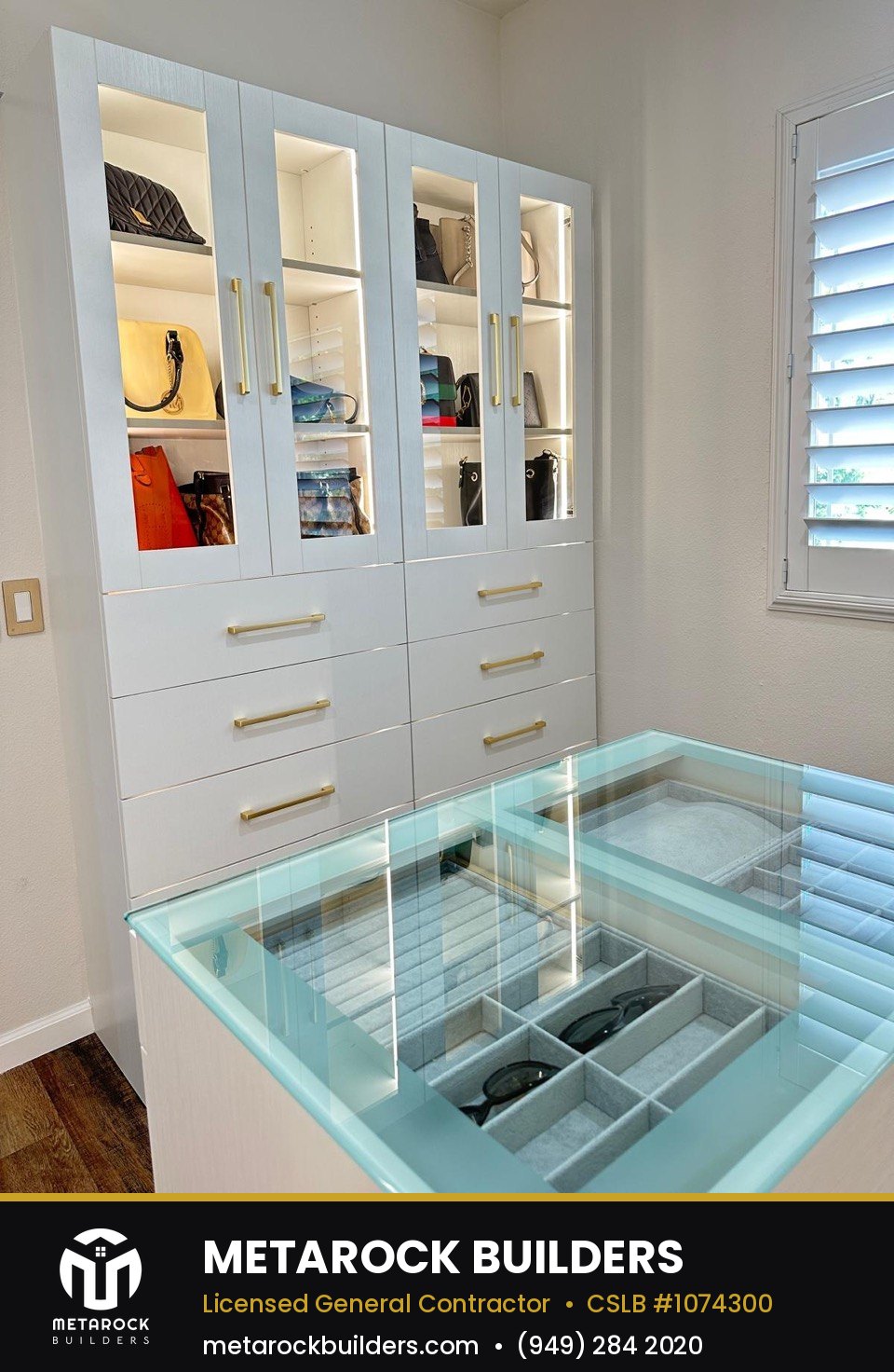 Closet remodel in Orange County by Sunward Builders Inc., completed after photo with glass-front cabinetry, brushed brass hardware, and glass-top accessory display
