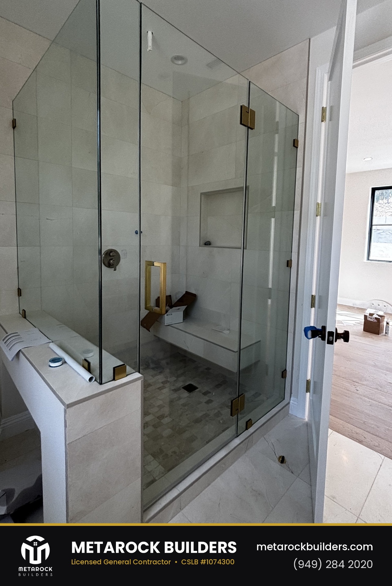 Shower remodel in Orange County by Sunward Builders Inc., completed after photo with frameless glass enclosure, brushed brass hardware, built-in bench, and large-format stone tile