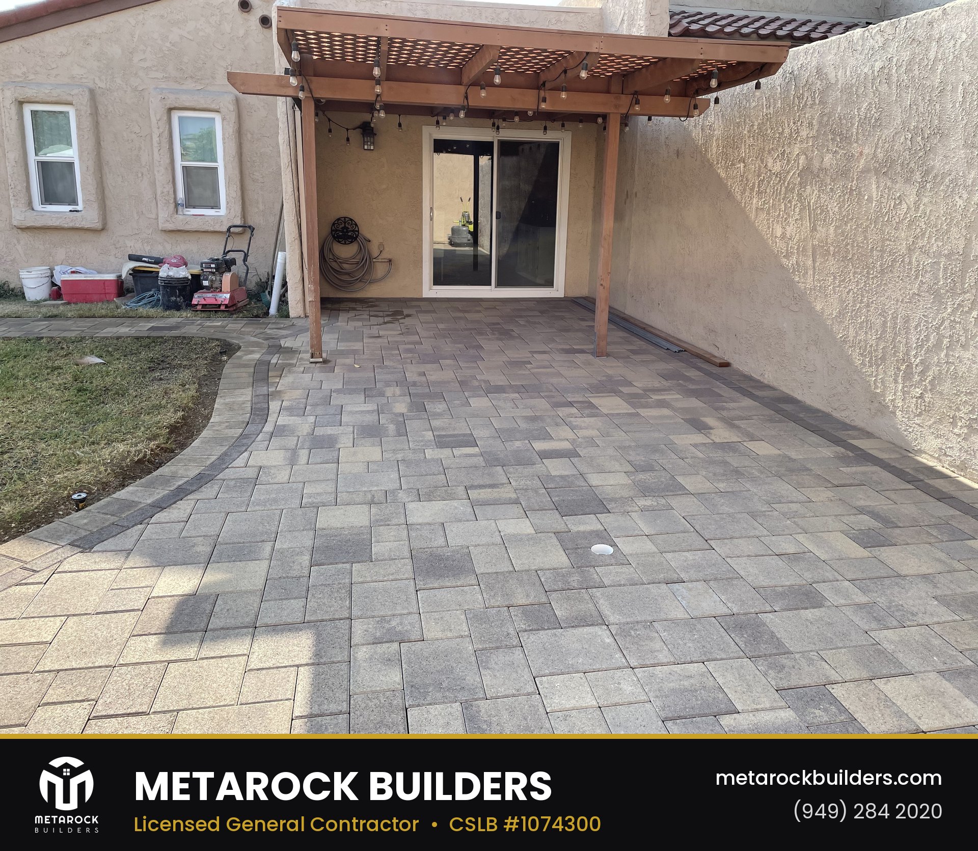 Paver patio in Orange County by Sunward Builders Inc., completed after photo with multi-tone stone pavers, curved lawn border, wood pergola, and string lights