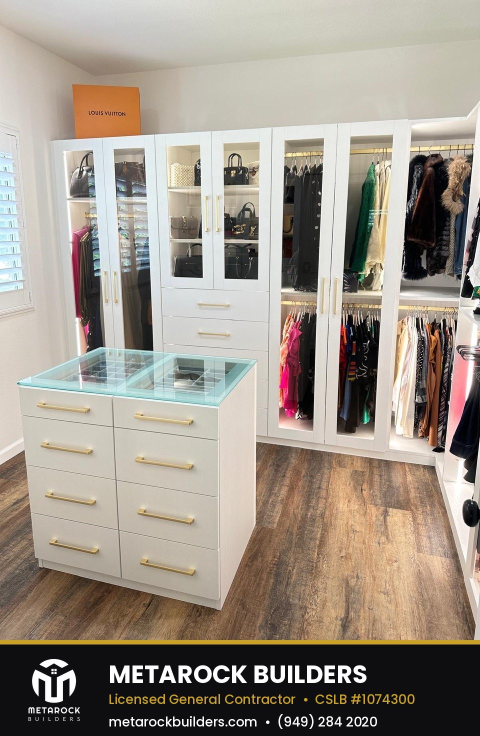 Closet remodel in Orange County by Sunward Builders Inc., completed after photo with full-wall wardrobe system, glass-front cabinets, and center island with glass top