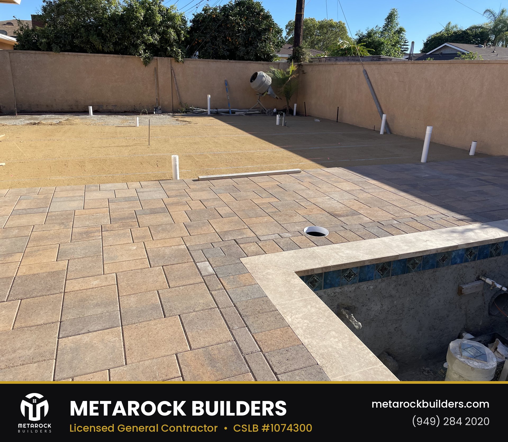 Paver patio and pool deck in Orange County by Sunward Builders Inc., in-progress photo with warm-tone stone pavers in basketweave pattern, travertine pool coping, and mosaic tile pool waterline