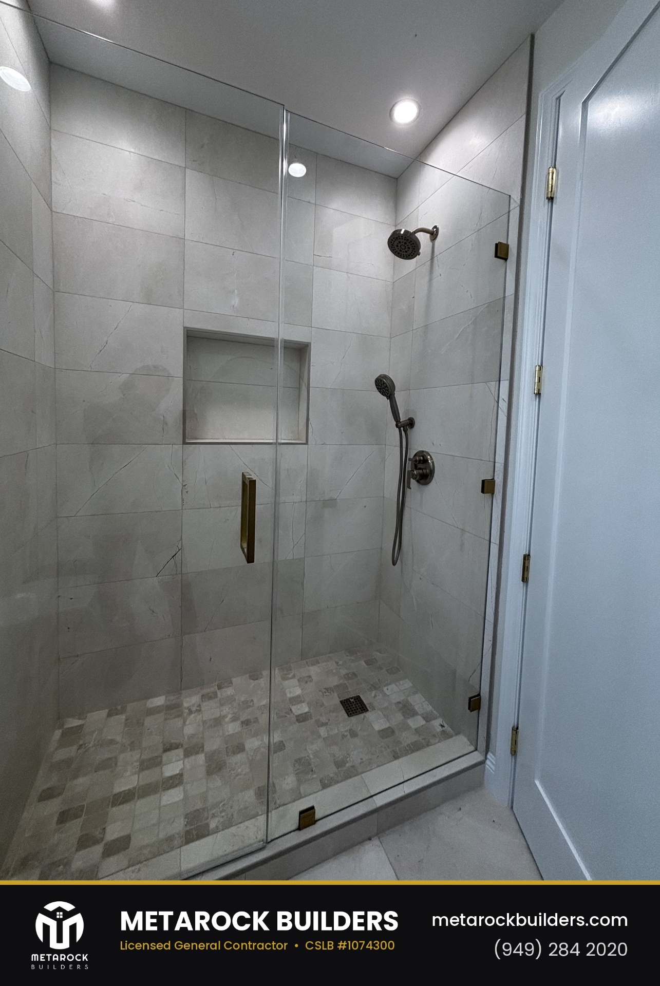 Shower remodel in Orange County by Sunward Builders Inc., completed after photo with large-format marble-look tile walls, frameless glass enclosure, brushed brass hardware, built-in niche, and stone mosaic floor