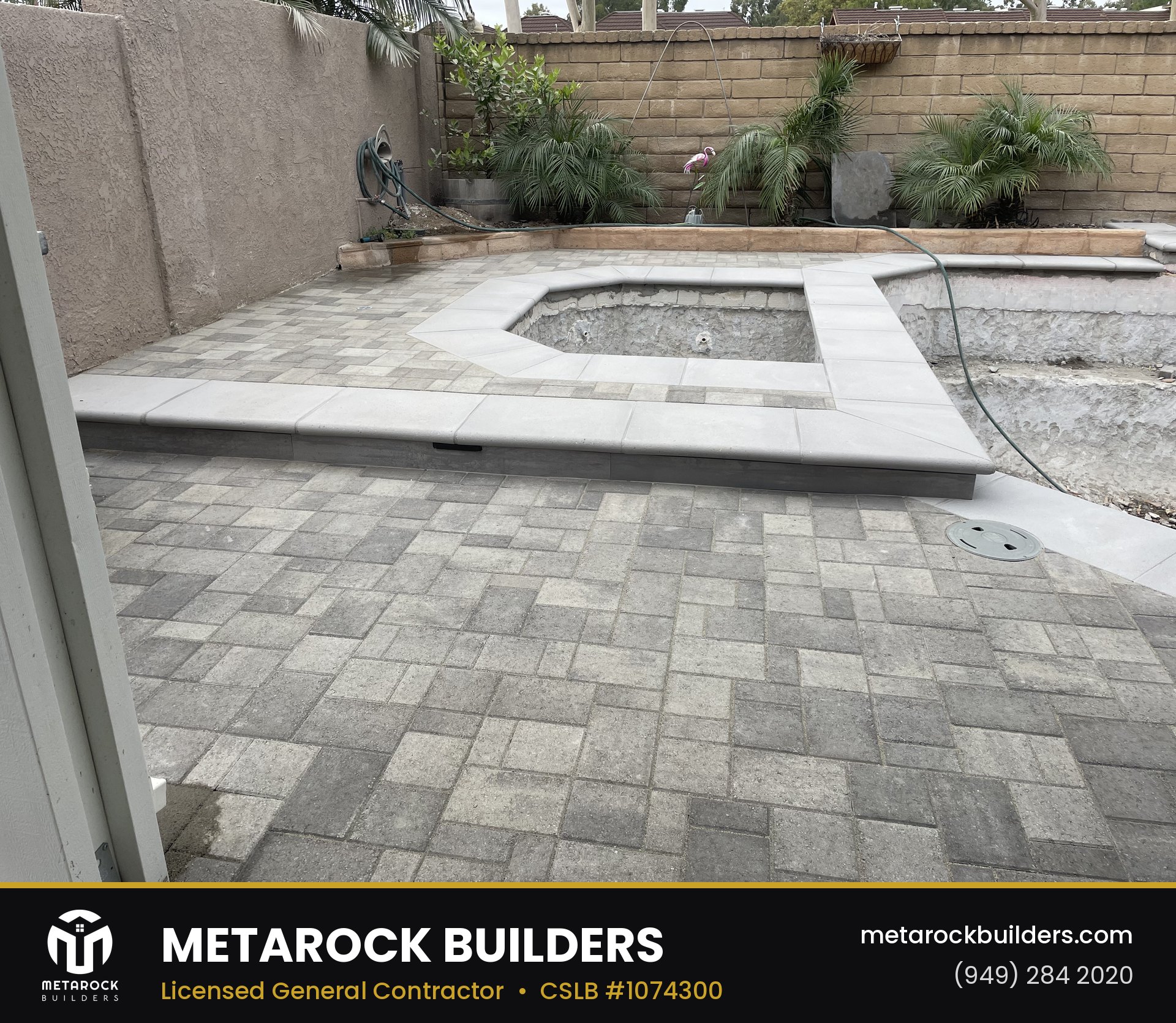 Landscaping in Orange County by Sunward Builders Inc., completed after photo with gray paver patio, raised spa surround with poured concrete coping, and planted retaining wall